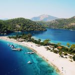 A beach in Dlaman Turkey surrounded by striking blue waters.